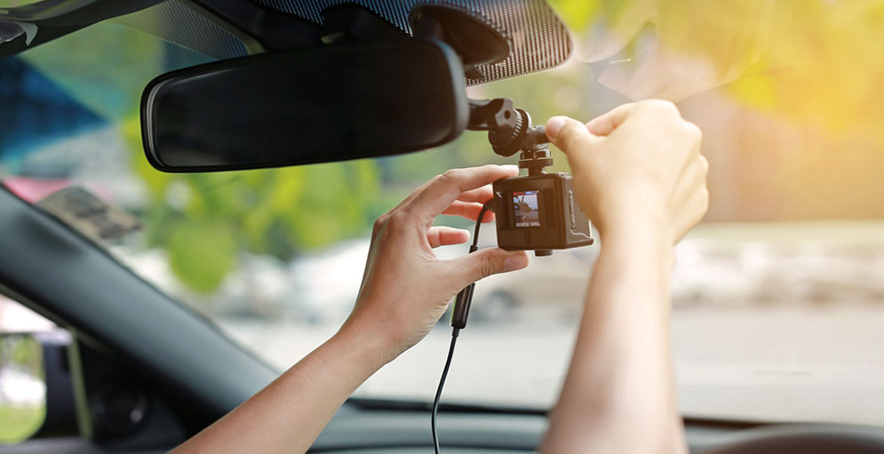 Someone inserting a dashcam to their car windscreen