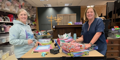 Two happy women sorting through donations at a charity shop