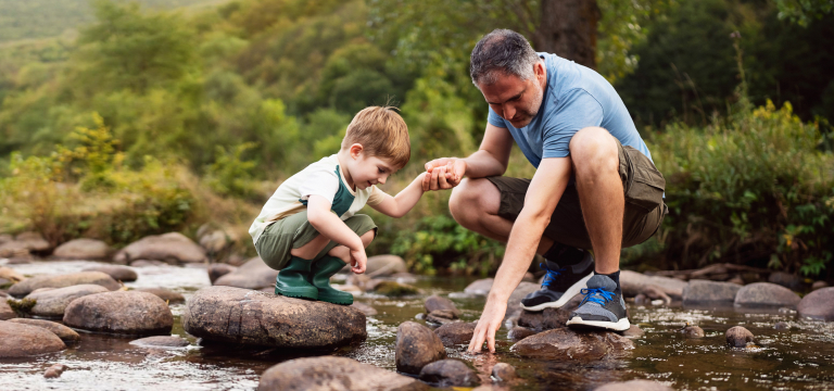 father and son playing in river