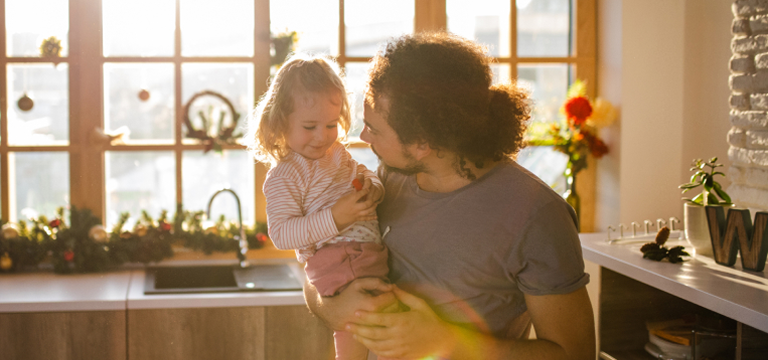 man holding his daughter in kitchen