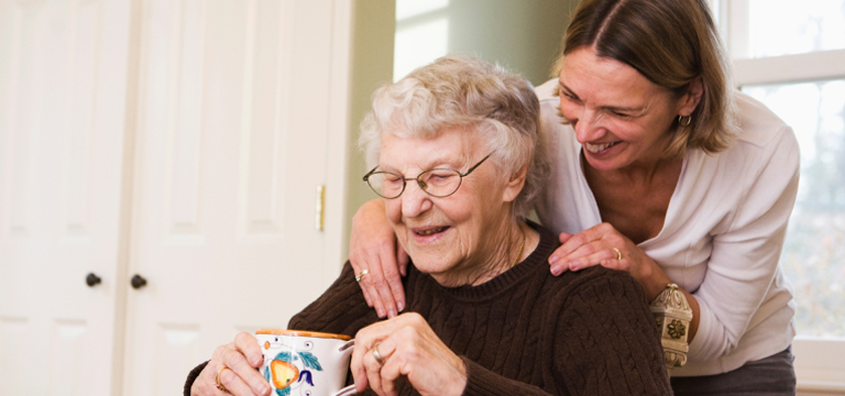 daughter leaning over elderly mother shoulder
