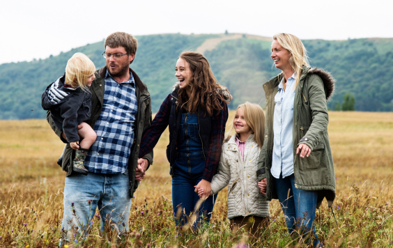 Young parents with three children walking through a field