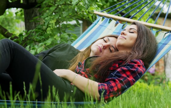 Two content women sleeping in a hammock outside