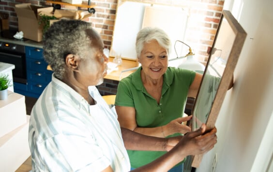 Happy senior couple hanging a picture on the wall in their new home