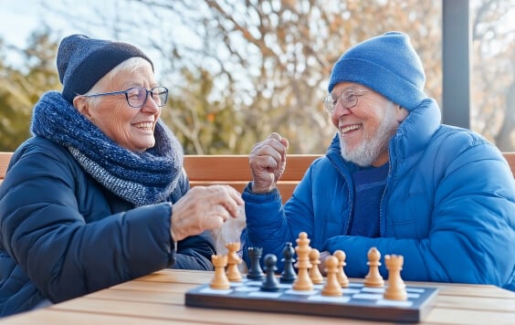 Senior couple playing chess, laughing together