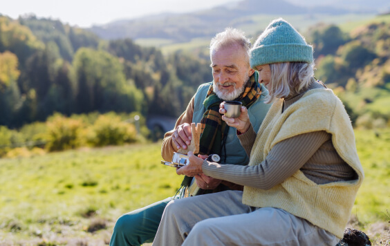 Older couple sat in a field with a drink