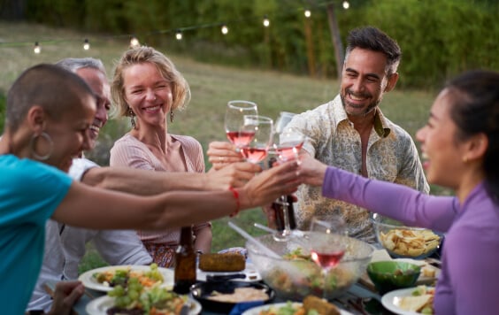Group of middle-aged friends dining together on the terrace of a house