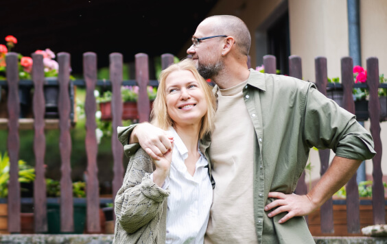 Happy relaxed middle age couple enjoying summer in country house standing on hugging in garden