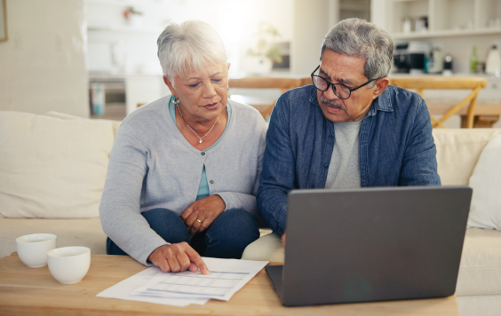 older couple on couch with laptop and paperwork