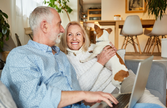 older man and woman on sofa with dog smiling