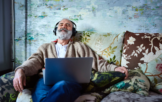 Man with laptop and headphones on a sofa