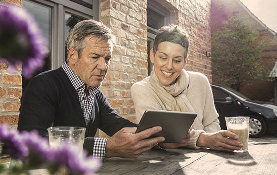 Man and woman look at a tablet in a sunny beer garden
