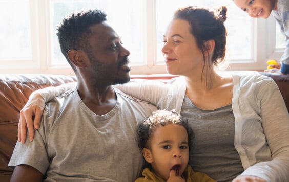 Affectionate multi-ethnic young family on living room sofa