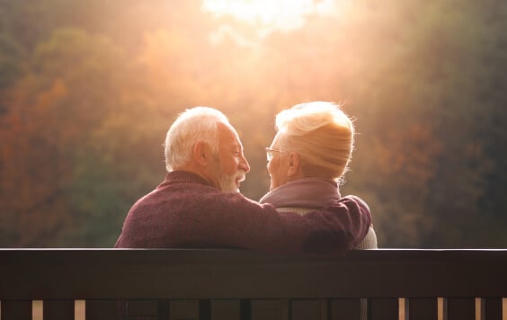 Senior couple sitting on bench in autumn park