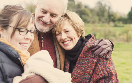 Grandparents smiling at daughter and grandchild