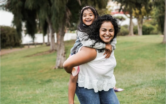 Happy Mother giving young, laughing daughter a piggyback
