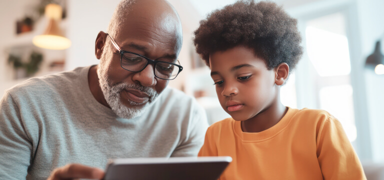 Grandfather and grandson looking intently at an ipad