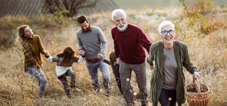 Multigenerational family holding hands walking up a hill for a picnic 