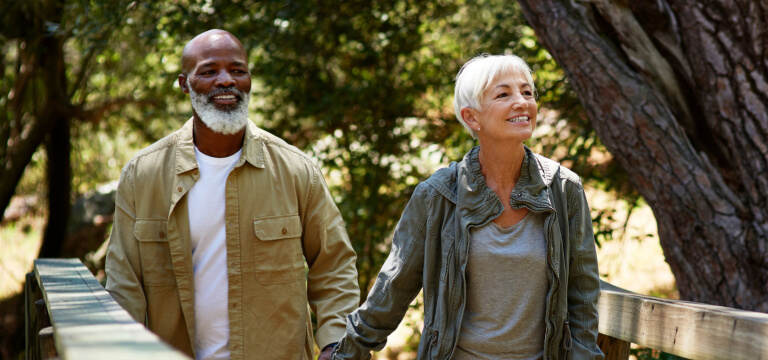 Interracial older couple walking hand in hand in nature