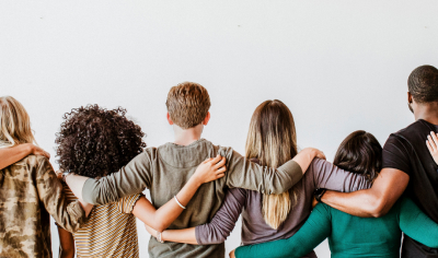 Line up of diverse individuals joining hands