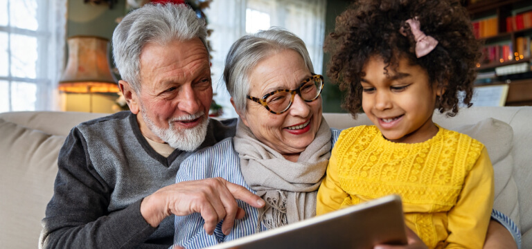 Grandparents and grandchild reading books on the sofa