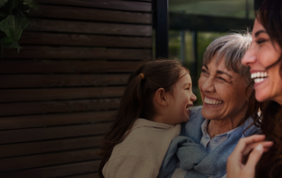 two women smiling while holding a child