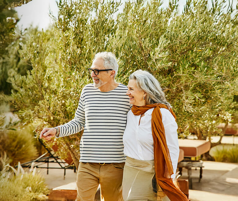 senior-couple-walking-on-grounds-of-luxury-resort-1920x860