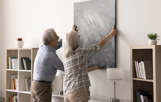 Older couple hanging up a painting