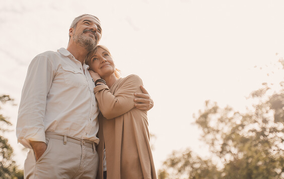 Older couple hugging look into the distance