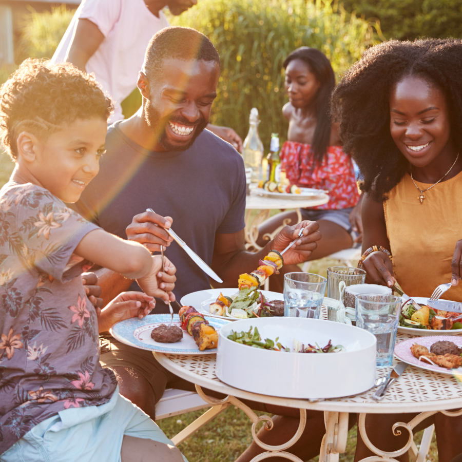 Family eating a meal outside gathered around the table