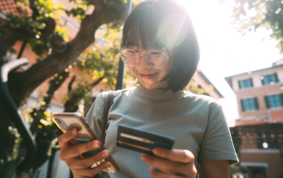 Woman smiling with her phone and bank card