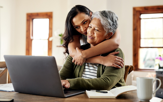 daughter hugging mother over laptop