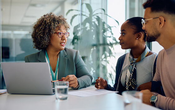 3 people in a meeting environment looking at a laptop