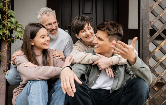 Smiling young man talking to family and sister while sitting on porch of house