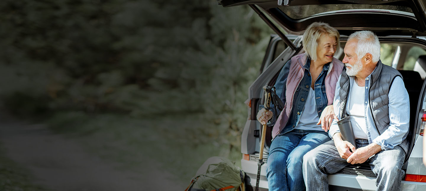 Older couple sitting in the boot of a car