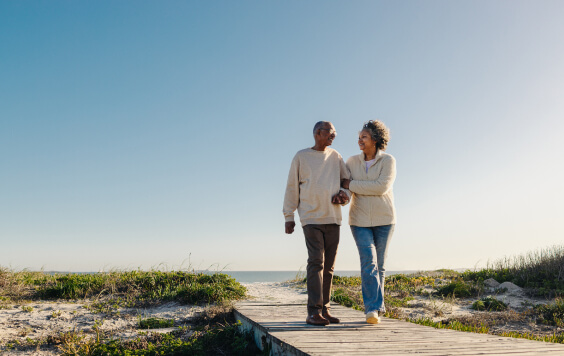 Romantic senior couple walking down a foot bridge at the beach 
