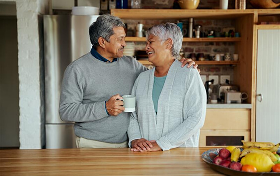 Older couple smiling at each other inside their home