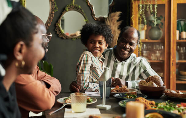 Grandfather and with young grandson sat on his knee at a family meal