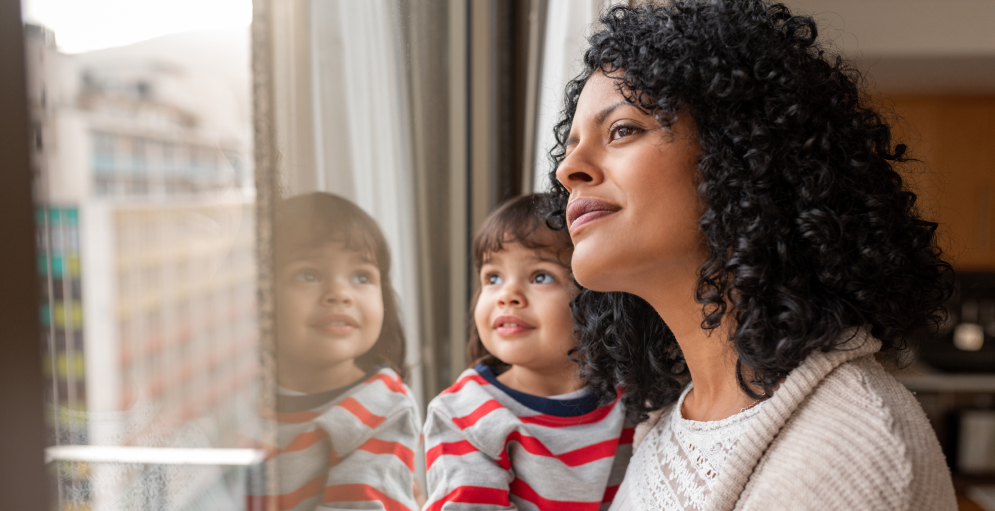 Happy mother and smiling daughter looking out of a window