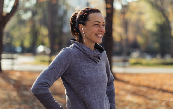 Female runner with earphones smiling in park