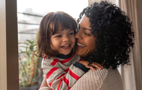 Loving mother hugging her cute little daughter at home