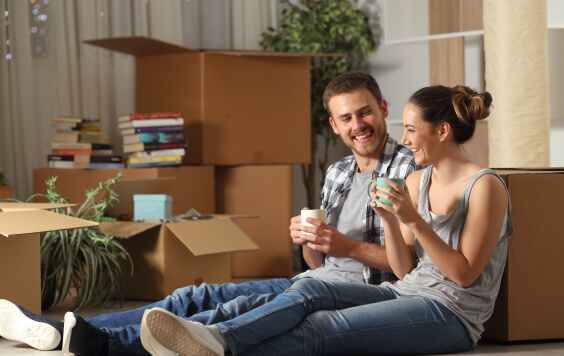 Happy-couple-moving-home-resting-and-talking-995x511