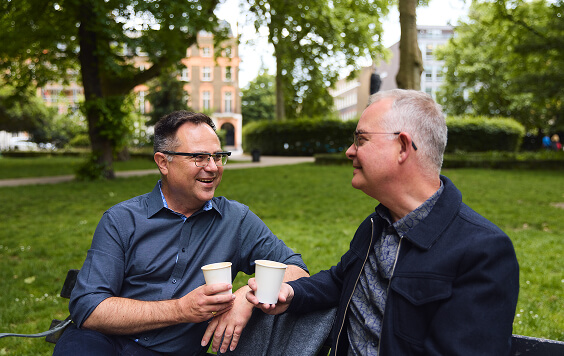 Two males sat chatting on a bench