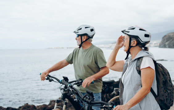 Two happy old mature people enjoying and riding bikes together to be fit and healthy outdoors