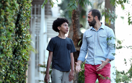 Father explaining something to his teenage son as they walk down the street