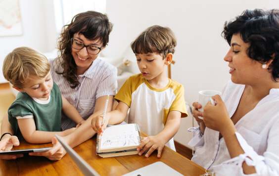 Couple sitting at dinning table with their two young children who are practicing writing