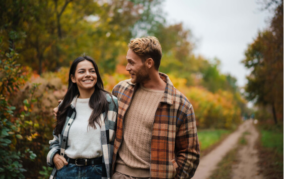 Beautiful happy couple smiling and hugging while strolling in forest 