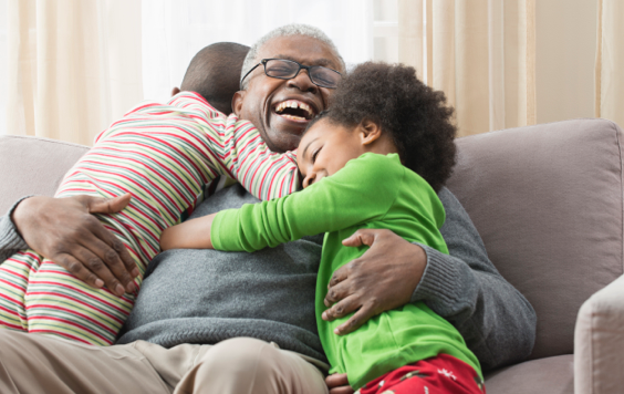 Man hugging grandchildren on sofa