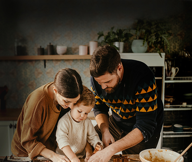 man, woman and child in a kitchen rolling pastry
