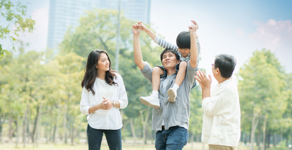mother and grandmother clapping as a father carries a young boy upon their shoulders